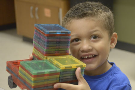 Wayne Township Preschool Student smiles while working with magnetic blocks!